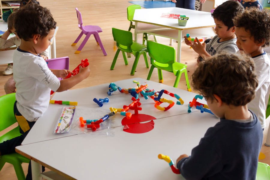 Niños jugando con bloques de construcción en un aula colorida del Lycée Français en Bogotá.