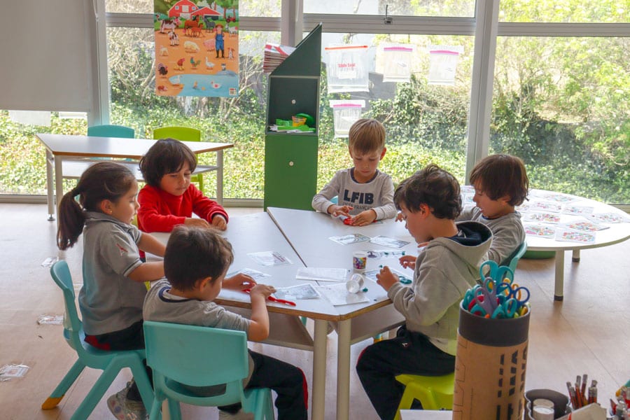Niños aprendiendo en aula del Lycée Français de Bogotá, participando en actividades educativas y creativas en un entorno moderno.